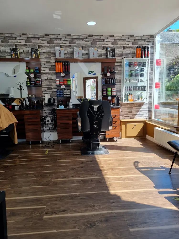 Shelves of hair styling products, waxes and clippers on the stone-clad wall of the barber shop
