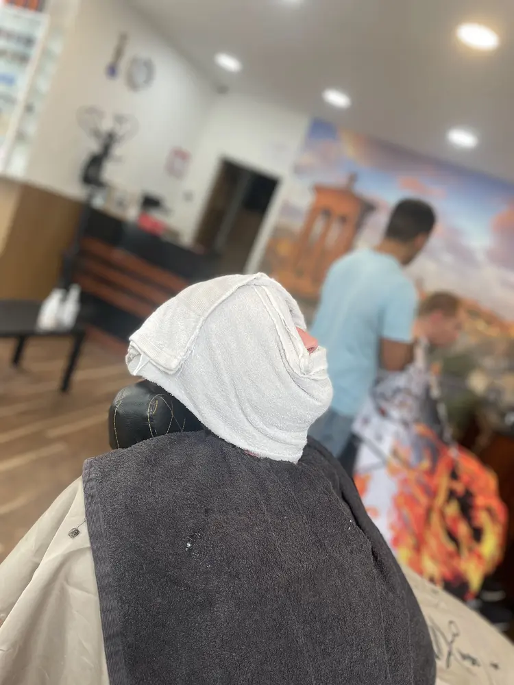 A customer reclined in the chair with a hot towel wrapped around his face